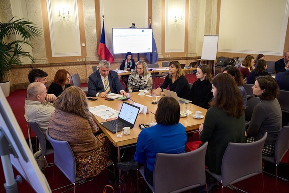 Účastníci konference sedí kolem stolu a diskutují